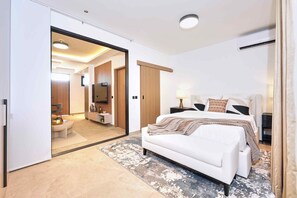 A modern bedroom with a large bed, a sofa, a TV, and a walk-in closet. - KORE -The Milton (Accra)