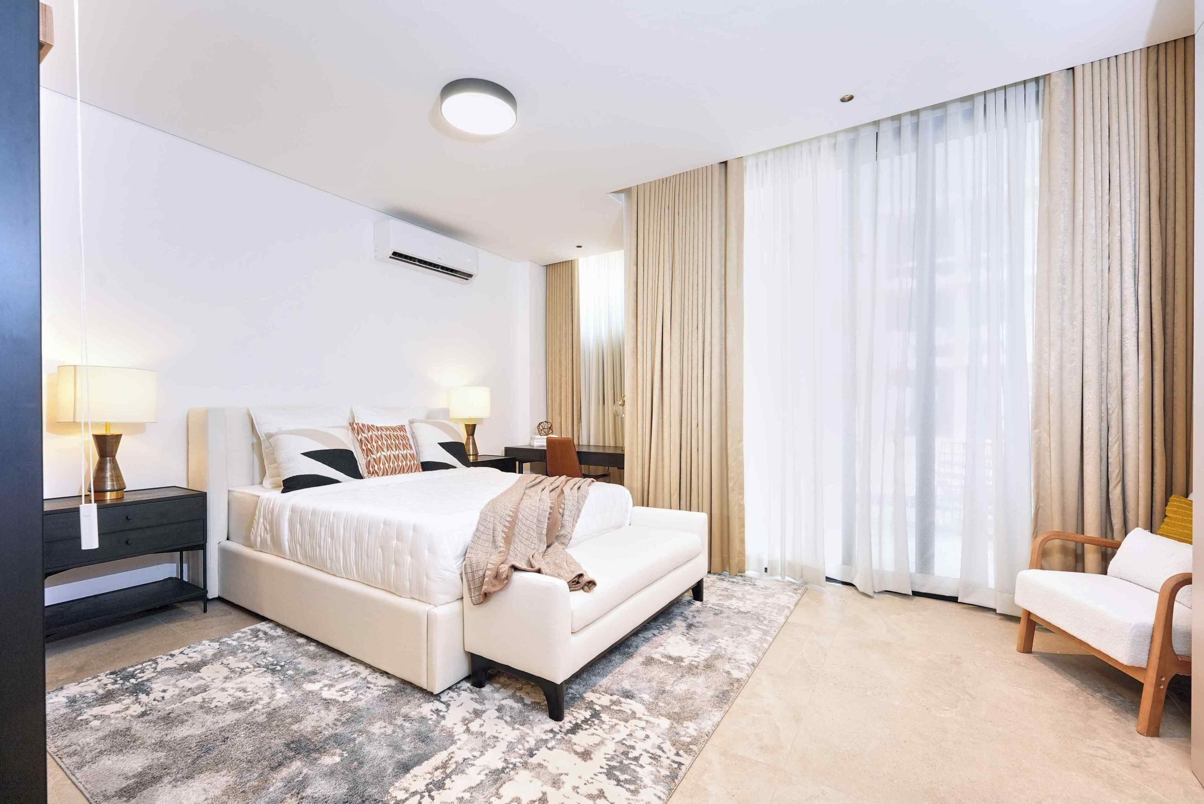 A hotel room with a large bed, two bedside tables, a chair, and a view of the outdoors.