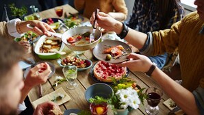 Un grupo de personas cenando en una mesa de madera con varios platos, incluyendo pizza y ensalada.