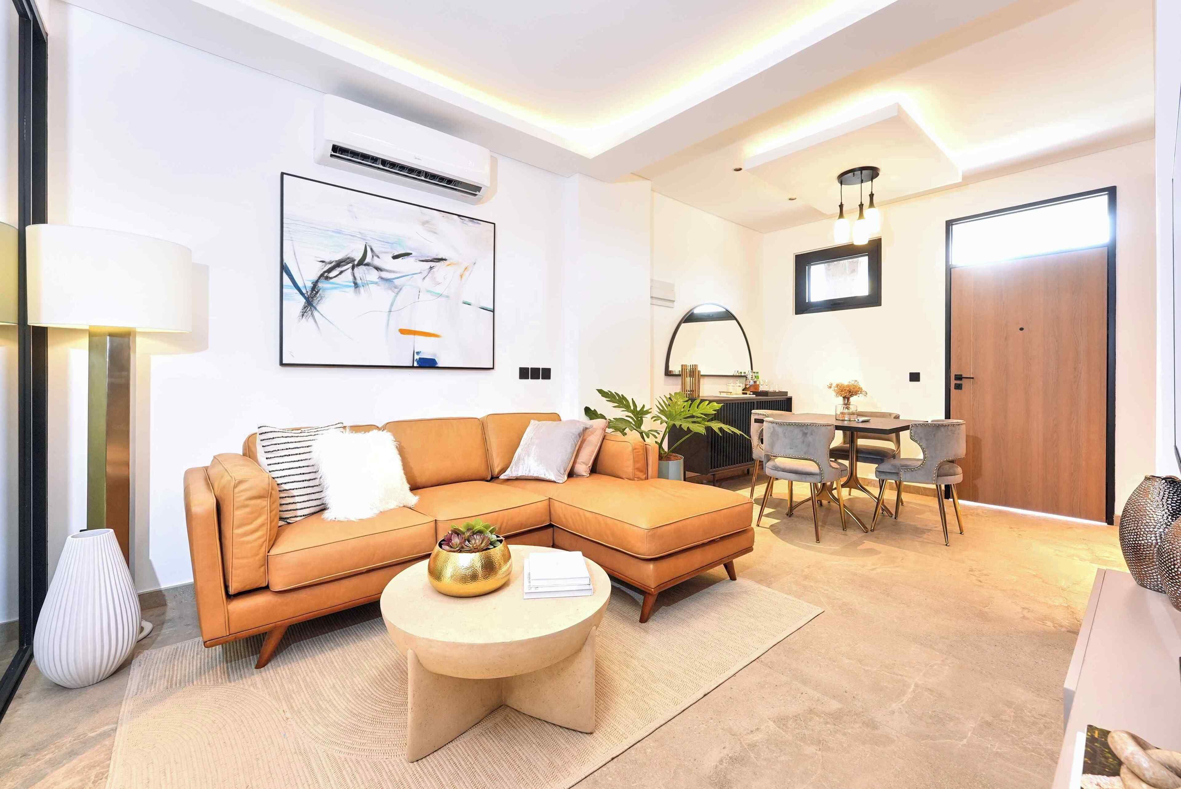 A modern living room with a sectional sofa, a round coffee table, and a dining area with a table and chairs.