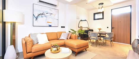 A modern living room with a sectional sofa, a round coffee table, and a dining area with a table and chairs.