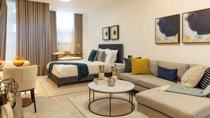 A modern hotel room with a bed, a sofa, a round coffee table, and artwork on the walls. - KORE -The Milton (Accra)