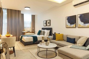 A modern hotel room with a bed, a sofa, a round coffee table, and artwork on the walls. - KORE -The Milton (Accra)