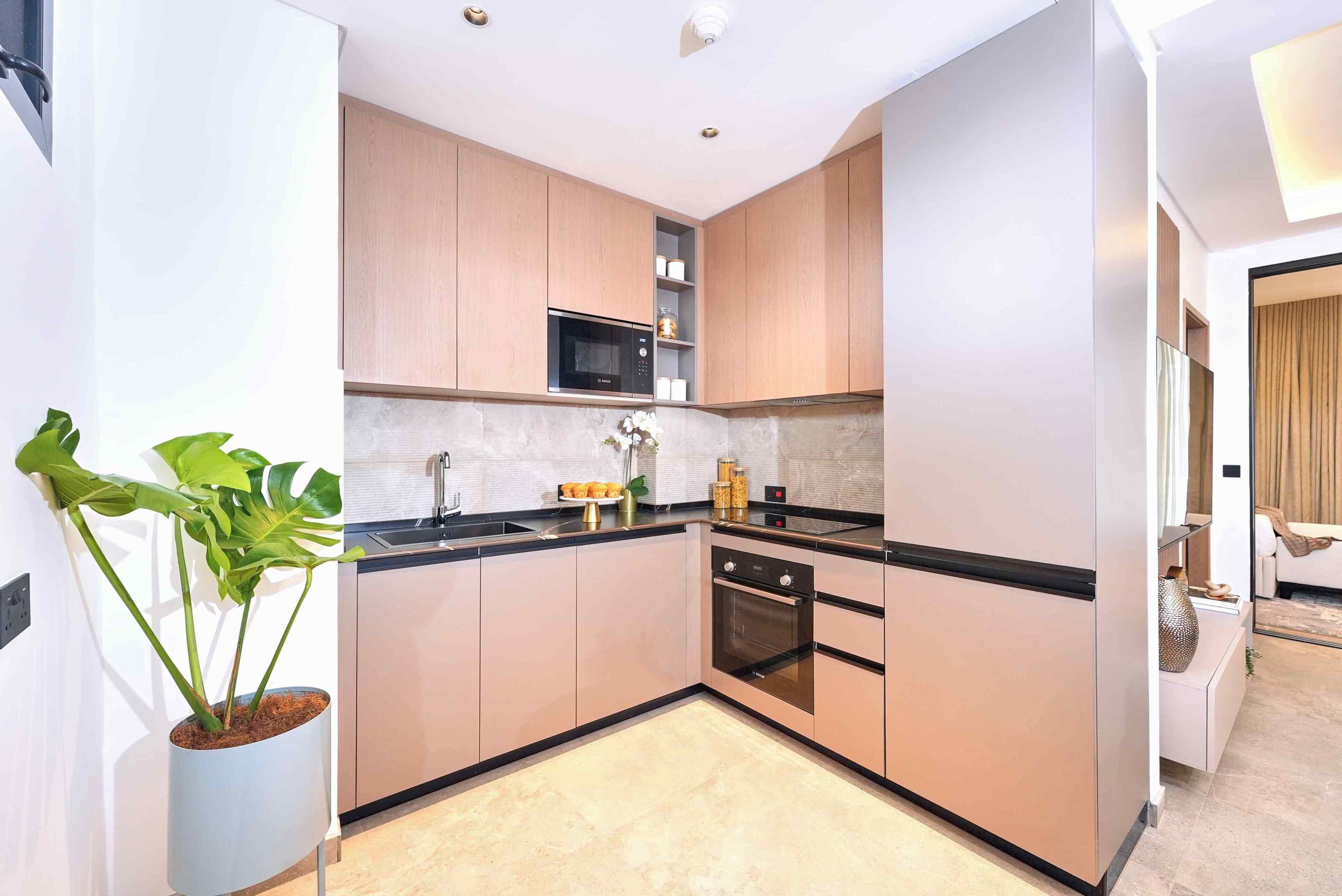 Una cocina moderna con armarios de madera, microondas integrado, un lavamanos y un horno.