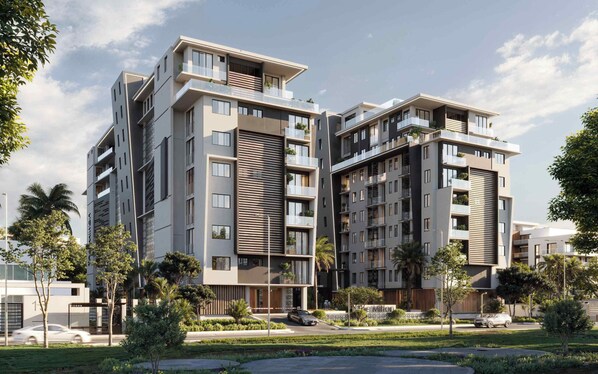A modern multi-story residential building with balconies, a landscaped garden, and a clear sky. - KORE -The Milton (Accra)