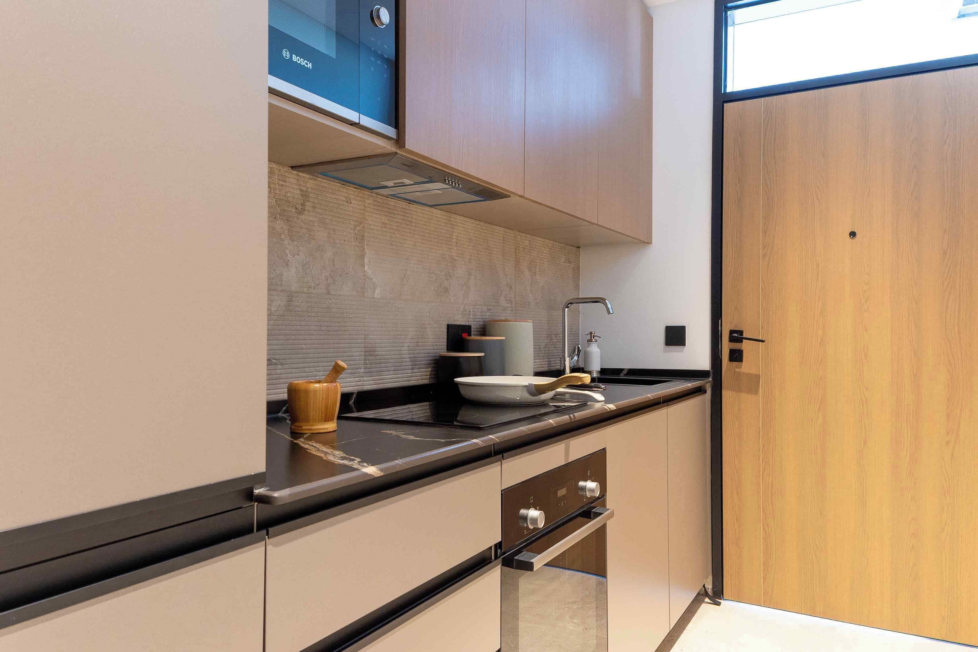 Een moderne keuken met een ingebouwde Bosch vaatwasser, een houten kast en een roestvrijstalen spoelbak.