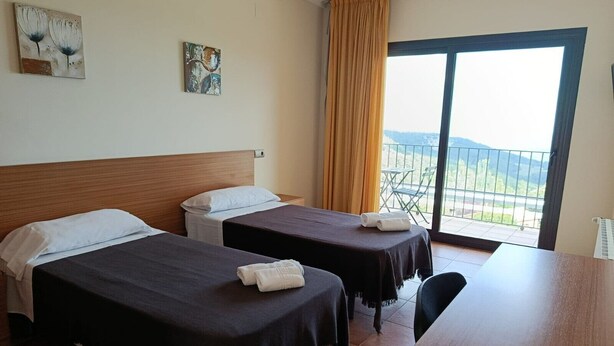 A hotel room with two beds, a wooden desk, and a balcony with a view. - Room 'Habitació Castanyer' with Sea View, Balcony and Wi-Fi (Mont-ral)