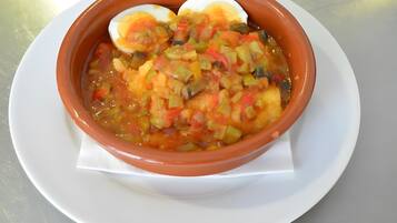 Un plato blanco con sopa, verduras y un huevo duro.