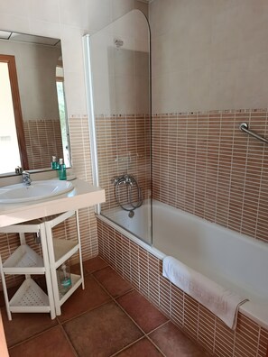 A bathroom with a sink, mirror, shower, and tiled walls.