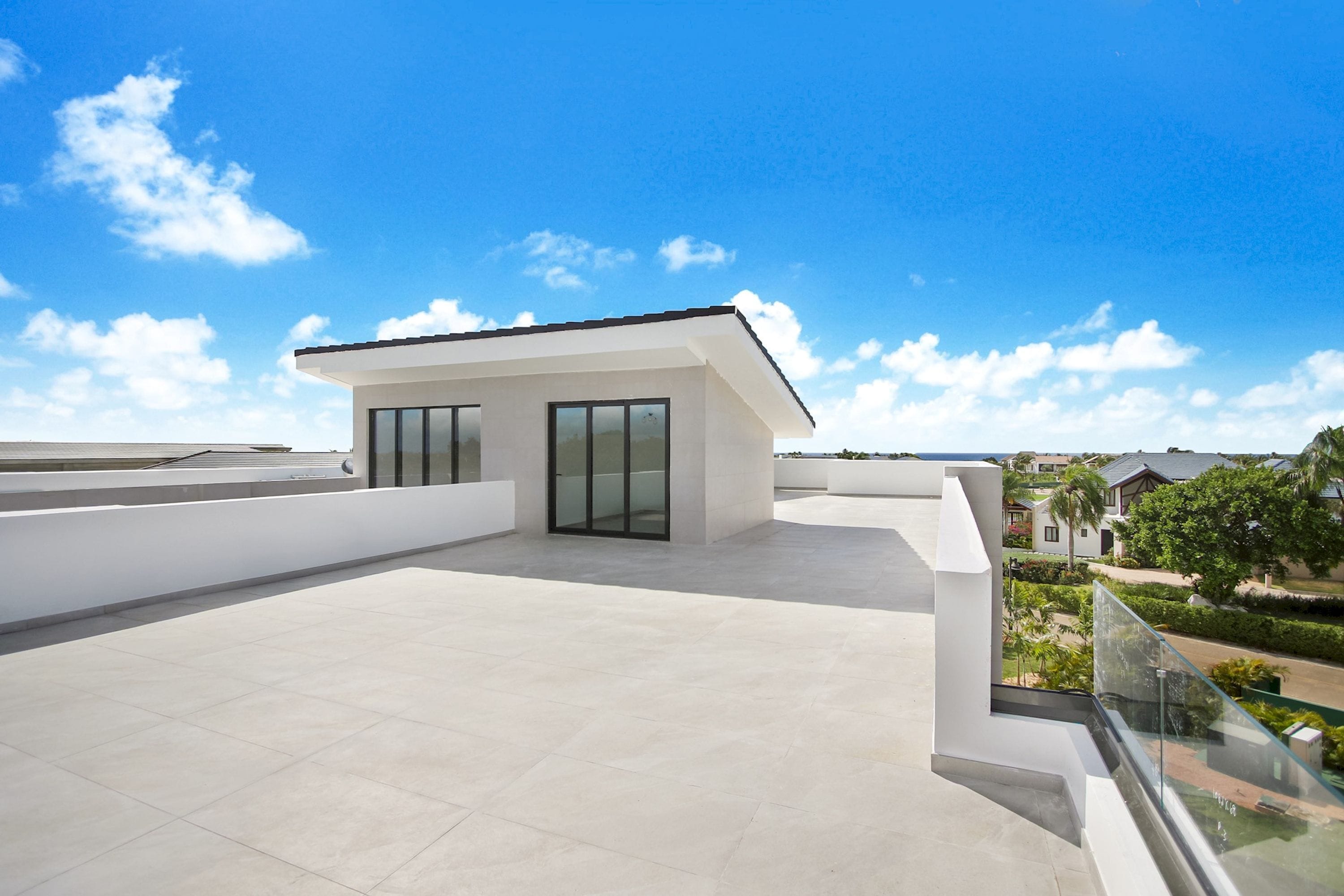 A modern building with a flat roof, large windows, and a view of a residential area.