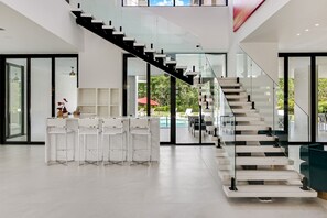 Ein modernes Interieur mit Treppe, Pool und Barbereich.