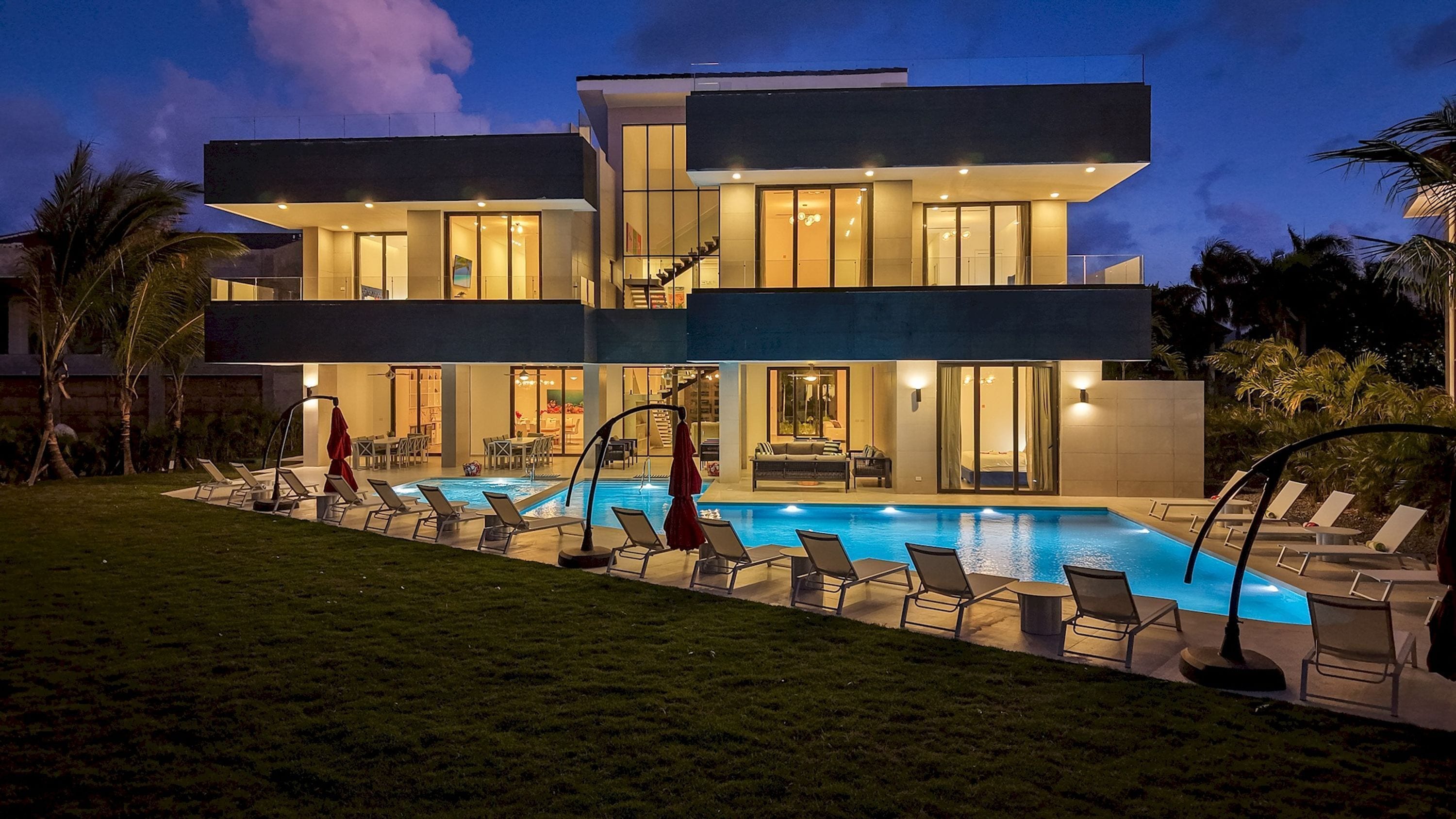 Ein modernes, zweistöckiges Gebäude mit Swimmingpool, Liegestühlen und einer Treppe.