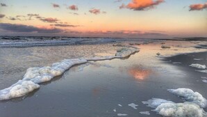 Een strand met golven en een zonsondergang.