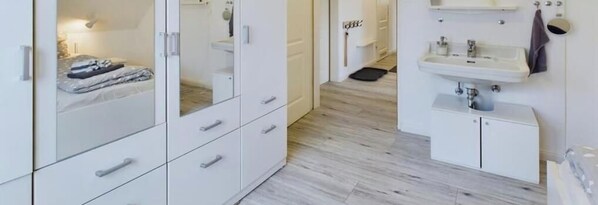Ein modernes Badezimmer mit Waschbecken, Spiegel und Stauraumschränken.