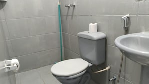 A bathroom with a toilet, a sink, and a shower. - Gyn Suítes Pedro Ludovico (Goiânia)