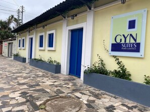 A building with a sign for 'GYN SUITES PEDRO LUDOVICO' and a tiled walkway. - Gyn Suítes Pedro Ludovico (Goiânia)