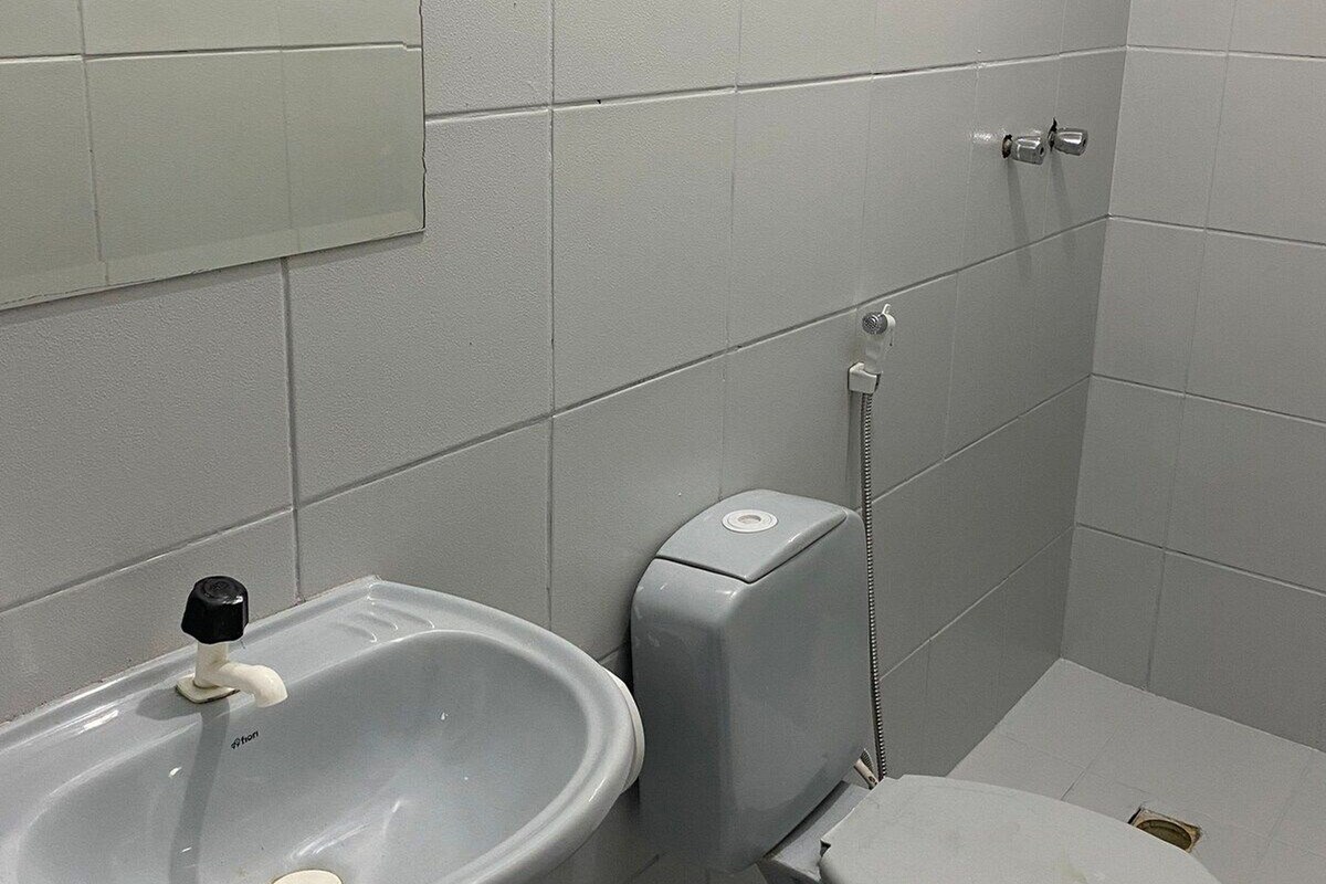 A bathroom with a pedestal sink, toilet, and a mirror on the wall.