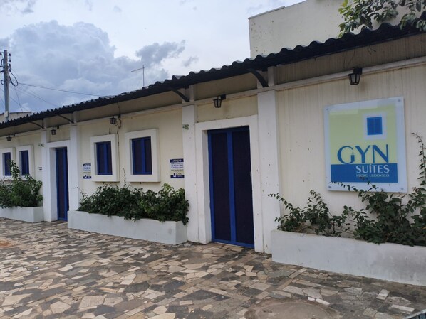 A building with multiple doors, some with blue frames, and a sign indicating 'GYN SUITES PEDRO LUDOVICO'.