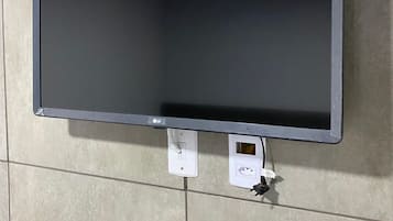 A flat-screen TV mounted on a tiled wall.