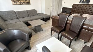 A living room with a sectional sofa, a coffee table, and leather armchairs. - Cozy Studio for 4 Near Floridsdorf (Vienna)
