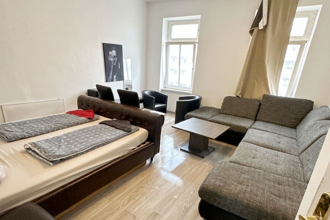 A compact living space with a bed, sofa, and a small table.