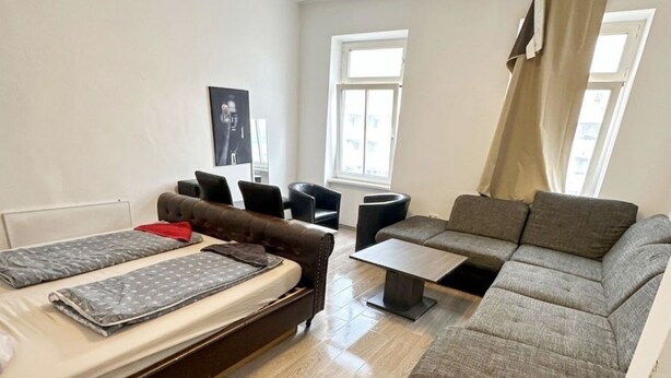 A compact living space with a bed, sofa, and a small table. - Cozy Studio for 4 Near Floridsdorf (Vienna)