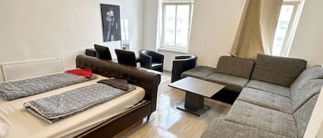 A compact living space with a bed, sofa, and a small table.