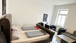 A room with a bed, two chairs, a sofa, and a window. - Cozy Studio for 4 Near Floridsdorf (Vienna)