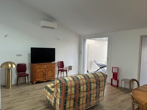 A living room with a sofa, television, wooden cabinet, and a red chair. - House for rent near Les Conches Beach (700 m) (Longeville-sur-Mer)