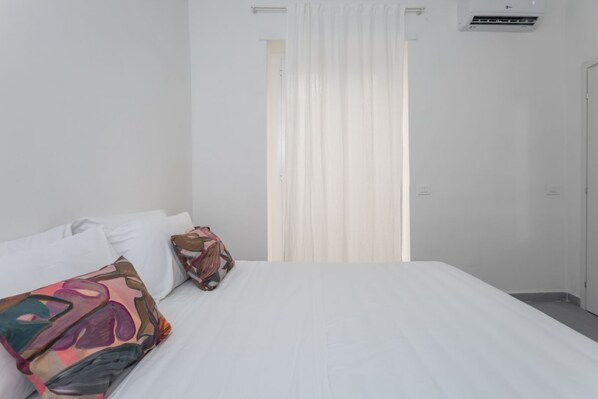 Een hotelkamer met een bed, witte gordijnen en een raam.