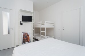 Een slaapkamer met stapelbedden, een televisie op een plank en een ingelijste foto aan de muur.