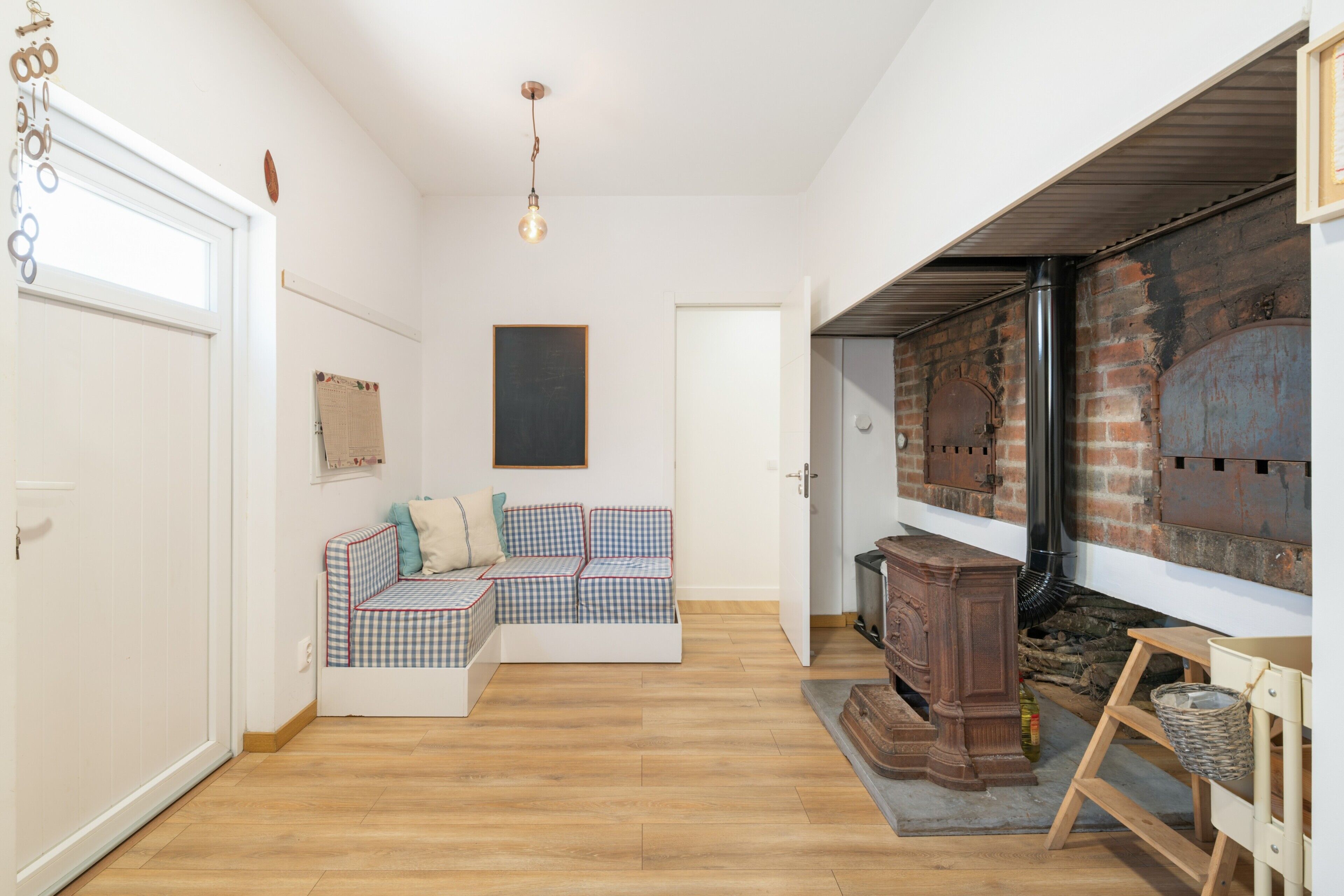 Una habitación acogedora con un sofá a cuadros, una chimenea y suelo de madera.