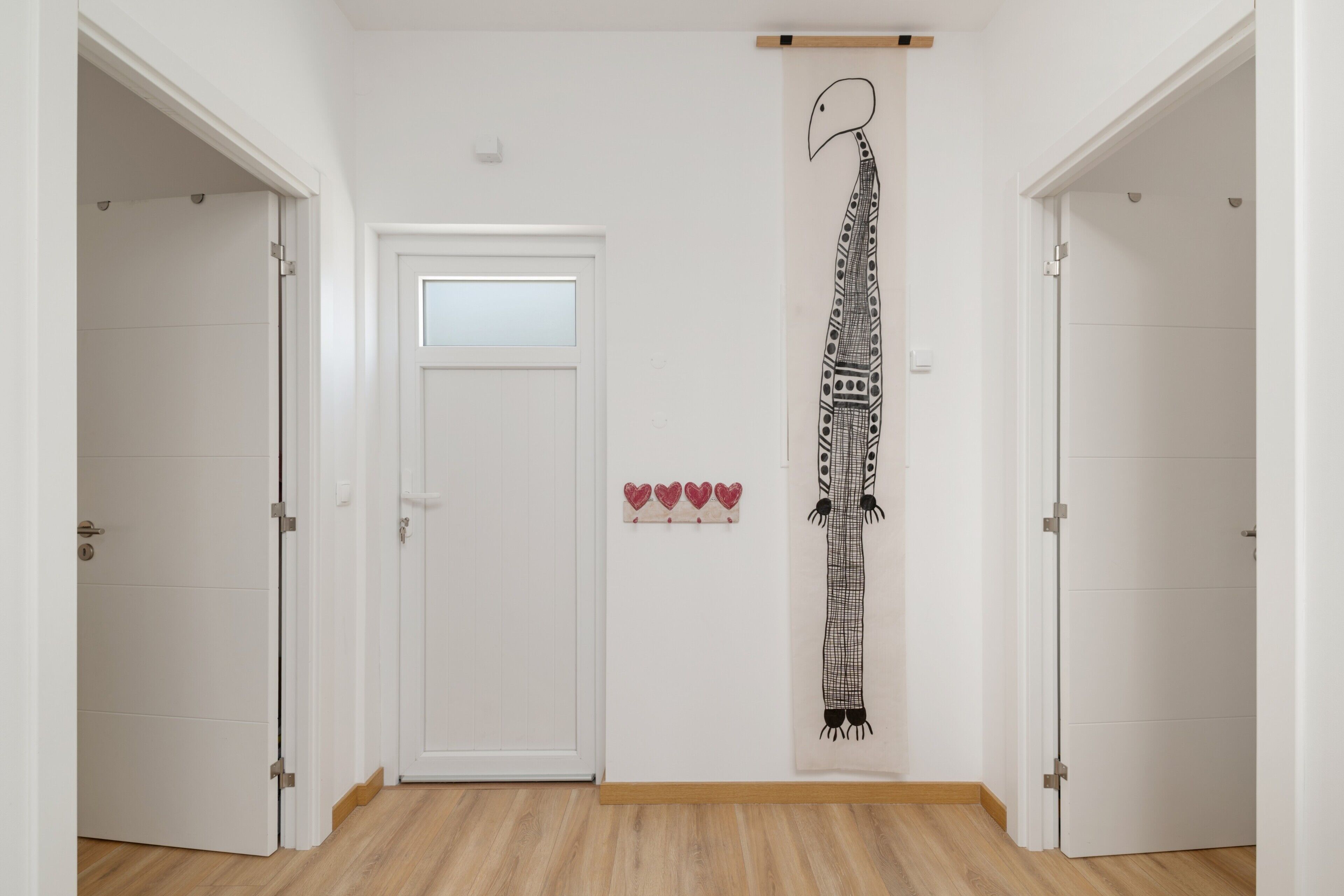 A hallway with white walls, a wooden floor, and a door with a frosted glass panel.