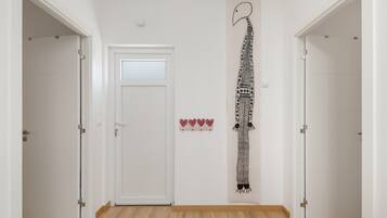 A hallway with white walls, a wooden floor, and a door with a frosted glass panel.