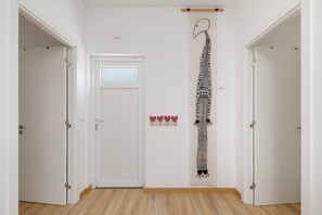 A hallway with white walls, a wooden floor, and a door with a frosted glass panel.