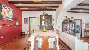 A dining area with a large table, chairs, and a red wall with a painting. - 'Excelentíssimo' Holiday Home with Lake View, Wi-Fi, and Air Conditioning (Torrão)