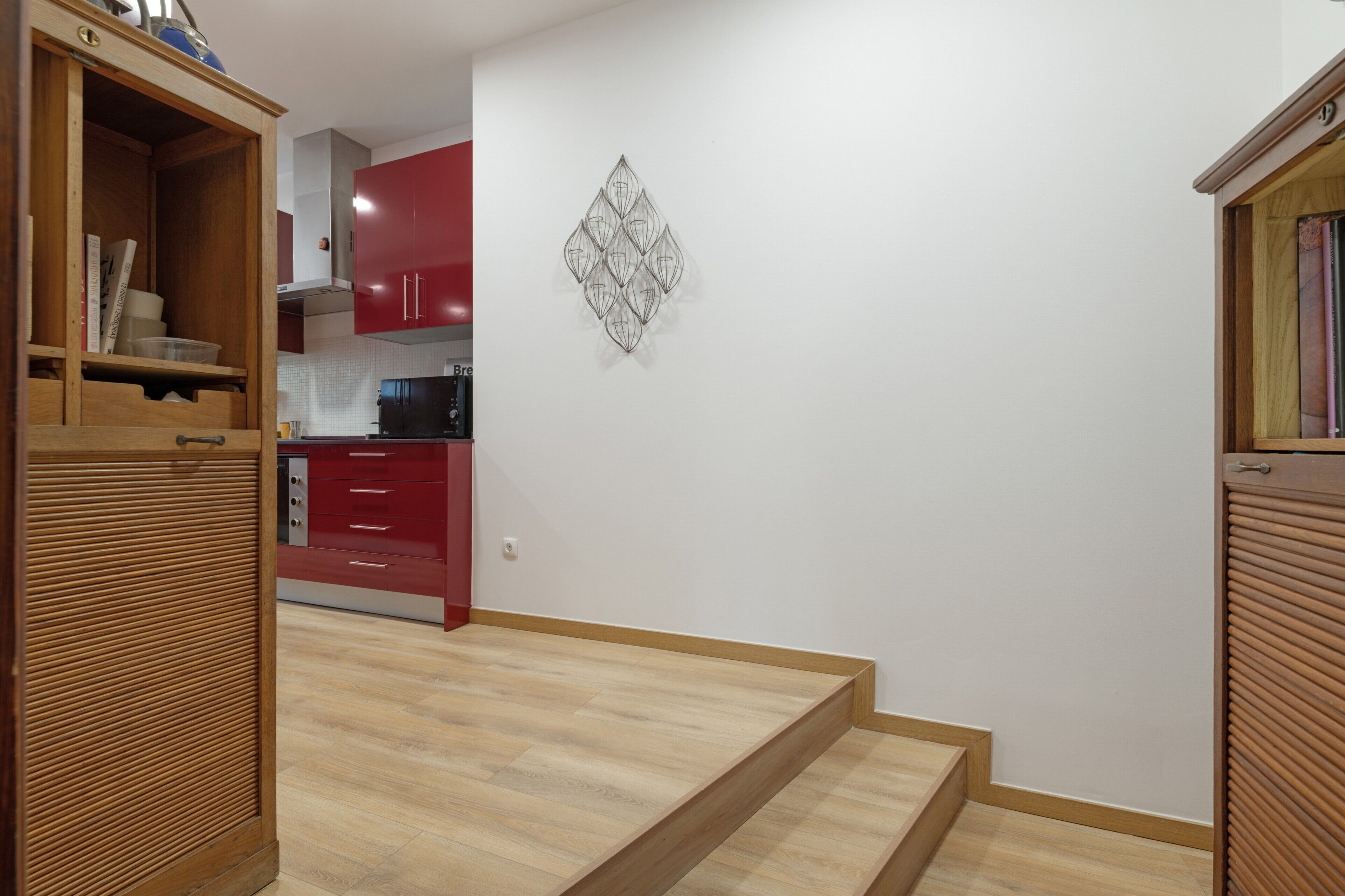 Eine moderne Küche mit roten Schränken, einem schwarzen Kühlschrank und einer Wandleuchte.