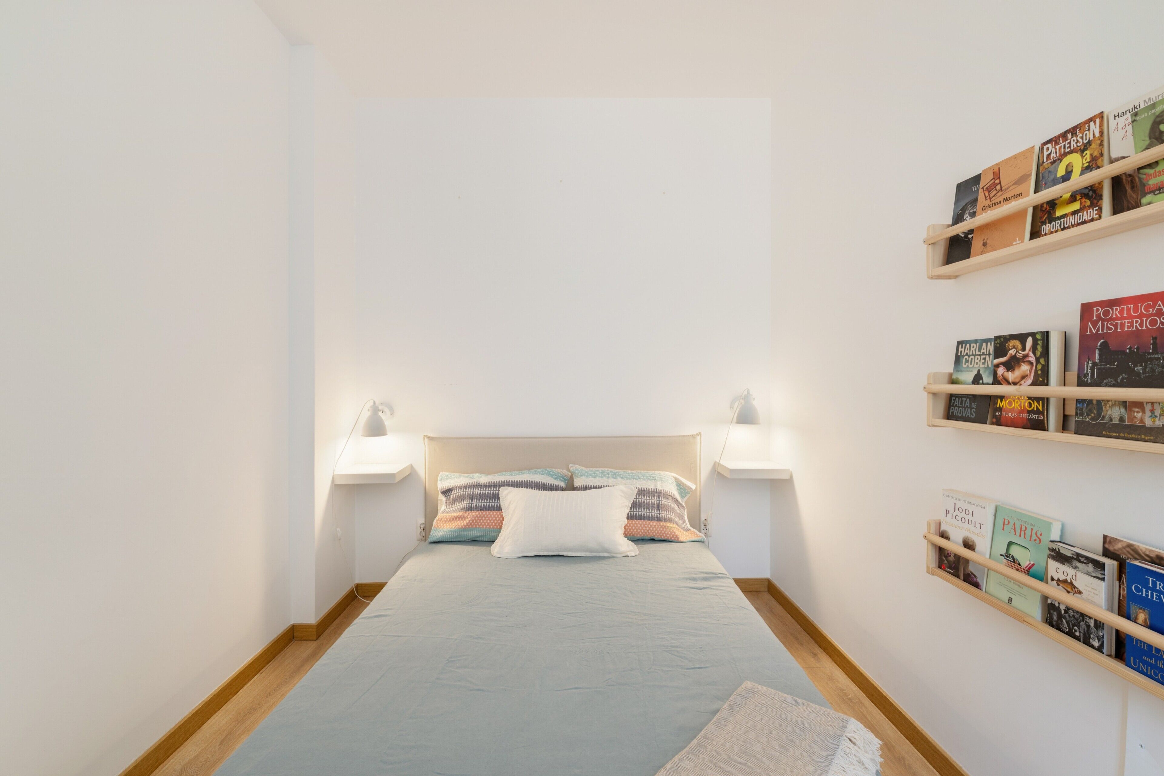 Une chambre à coucher avec un lit, des lampes de chevet, une table de chevet et un mur avec des étagères.