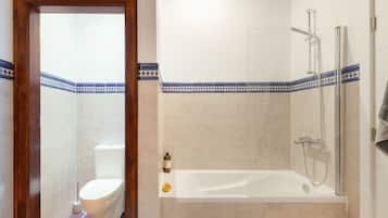 Un baño con inodoro, bañera y ducha.