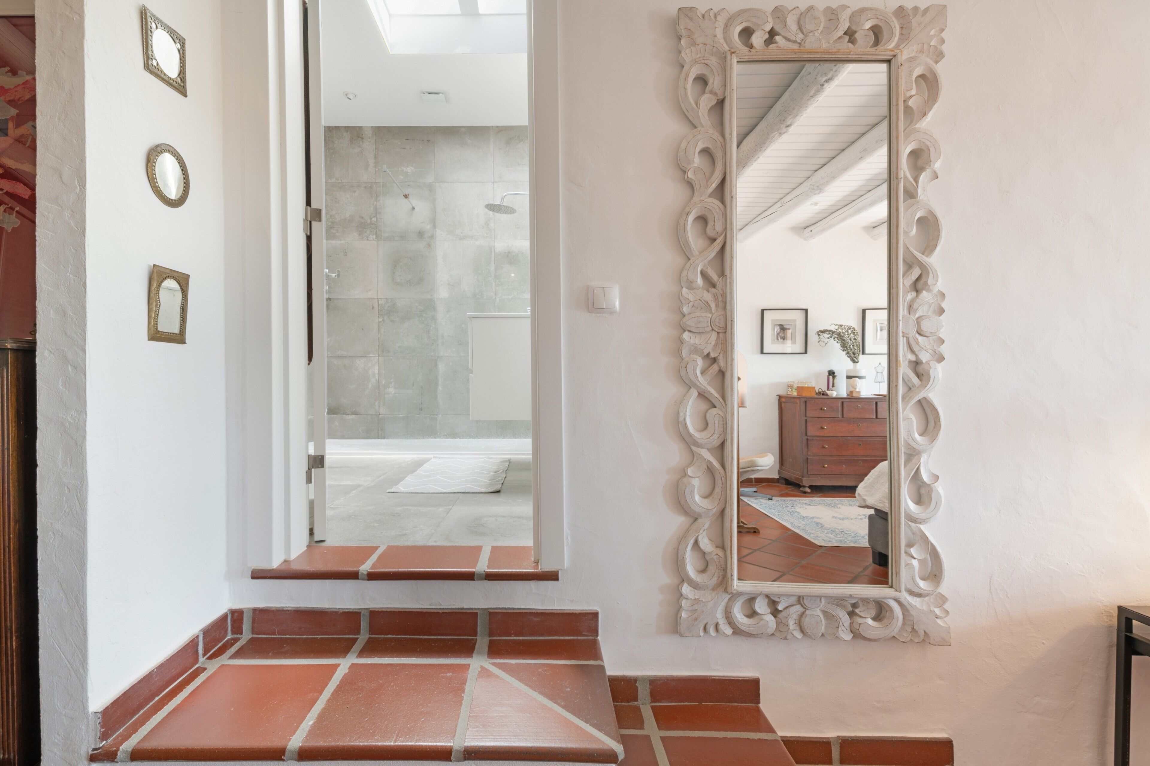 Un baño con ducha, espejo y piso de baldosas.