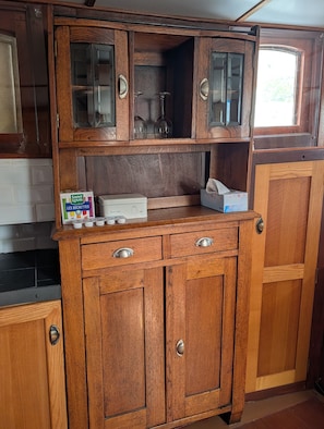 A wooden kitchen with a built-in cabinet, a box of Saint Louis beer, and a tissue box.