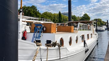 Ein weißes Boot liegt an einem Steg, in der Nähe befindet sich eine schwarze, zylinderförmige Struktur.