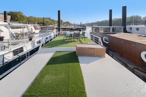 A boat deck with a grassy area, seating, and a view of the water.