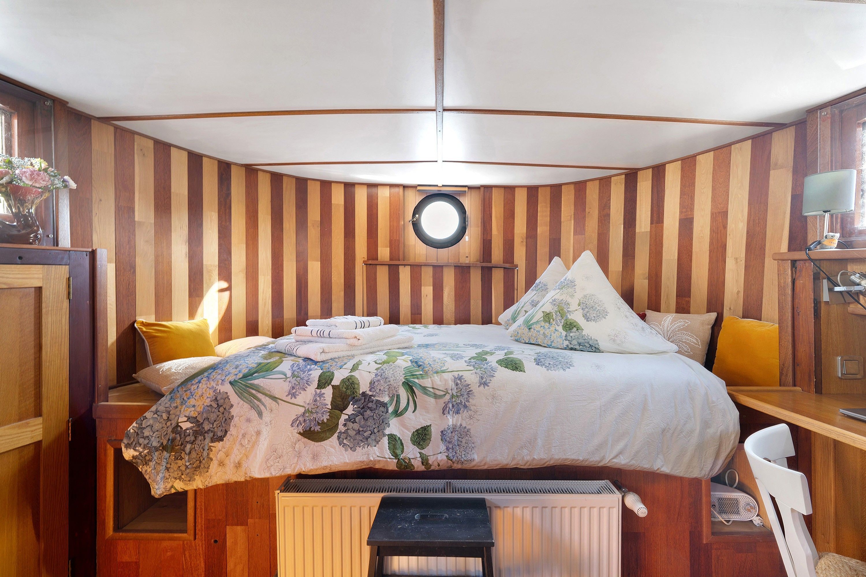 Une chambre à coucher avec un lit, un miroir rond, un bureau avec une lampe et une chaise.
