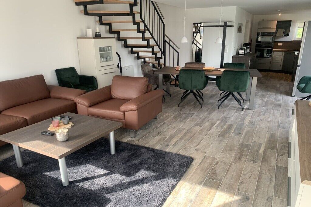 A modern living room with a sofa set, a coffee table, and a staircase leading to an upper level.