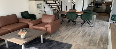 Una sala de estar moderna con un juego de sofá, una mesa de centro y una escalera que lleva a un nivel superior.