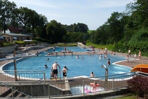 A public swimming pool with multiple lanes, surrounded by a fence and trees. - Holiday apartment with 2 bedrooms (Hohnstein)