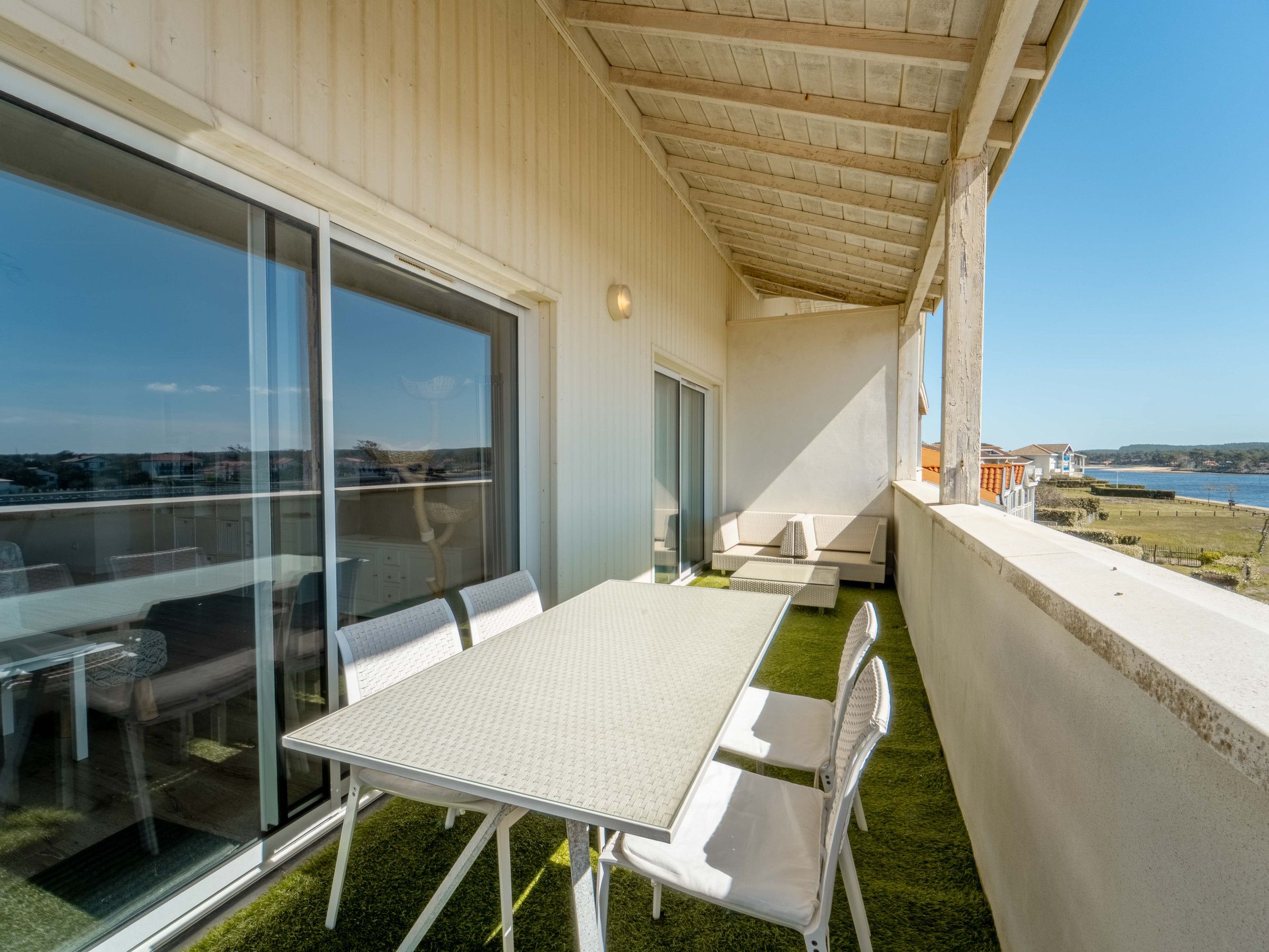 Un balcón con una mesa y sillas de comedor, un sofá y vista al mar.