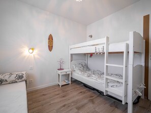 Ein Schlafraum mit Etagenbetten, einem kleinen Nachttisch, einer Wandleuchte und einer Surfbrett-Dekoration.