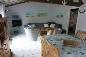 A cozy living room with a sofa, a dining table with chairs, a television, and artwork on the walls. - Holiday apartment with 2 bedrooms (Bredene)